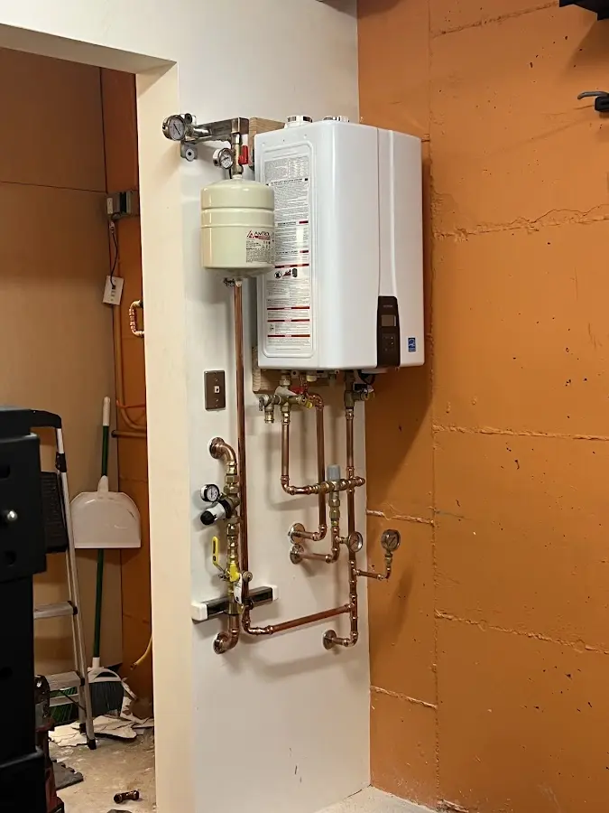 Plumbing technician inspecting water heater connections in Carmi